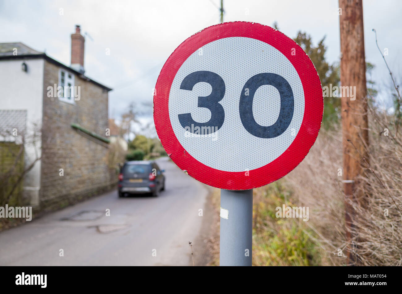 Segnale limite di velocità 30 KM/H su strada che attraversa un villaggio di campagna, Regno Unito, Dorset Foto Stock