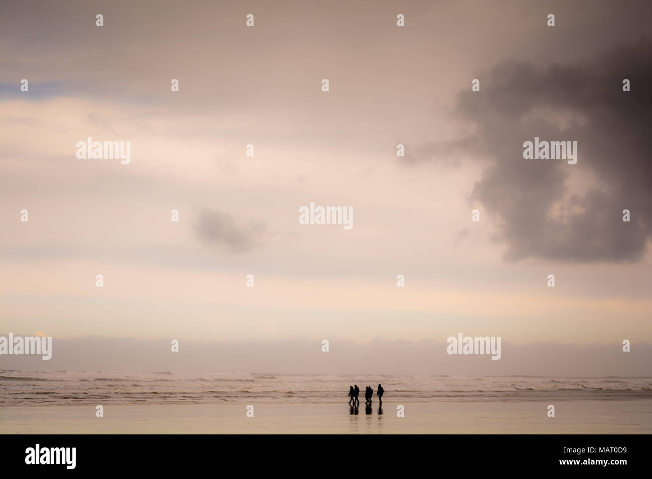 Gruppo di persone che camminano su di una spiaggia di sabbia in condizioni di bagnato Foto Stock