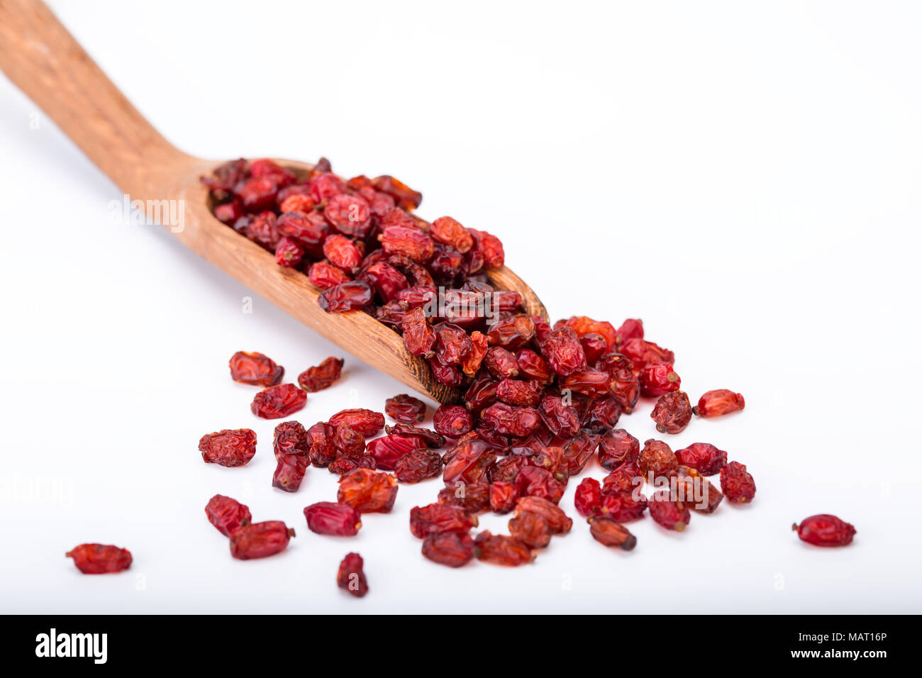 Close up e messa a fuoco selettiva di Barberries Frutta secca in un cucchiaio di legno isolato su sfondo bianco chiamato anche Zereshk e utilizzato per guarnire il riso Foto Stock