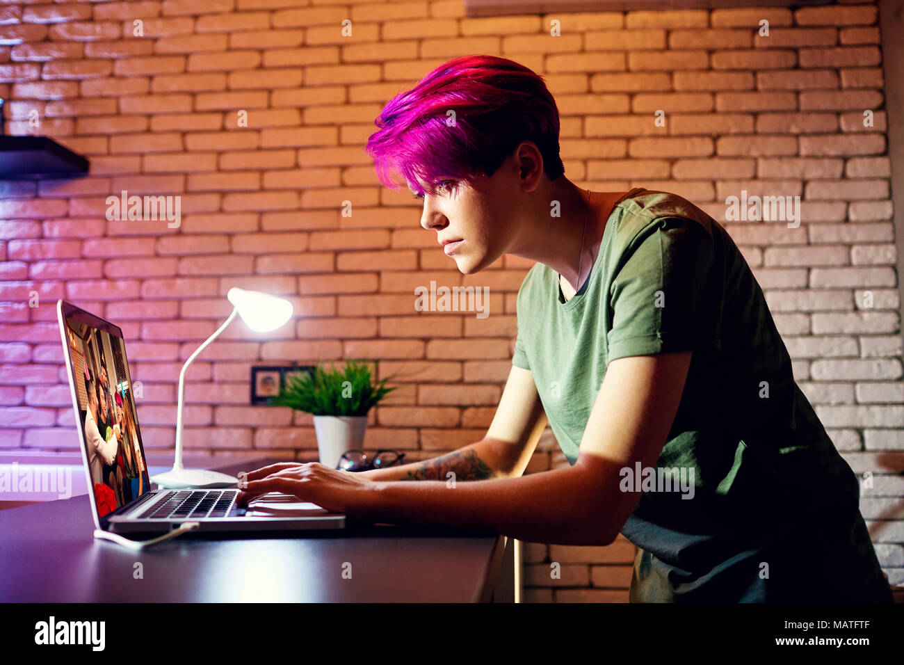 Ragazza giovane con i capelli colorati con un computer portatile sul tavolo. Foto Stock