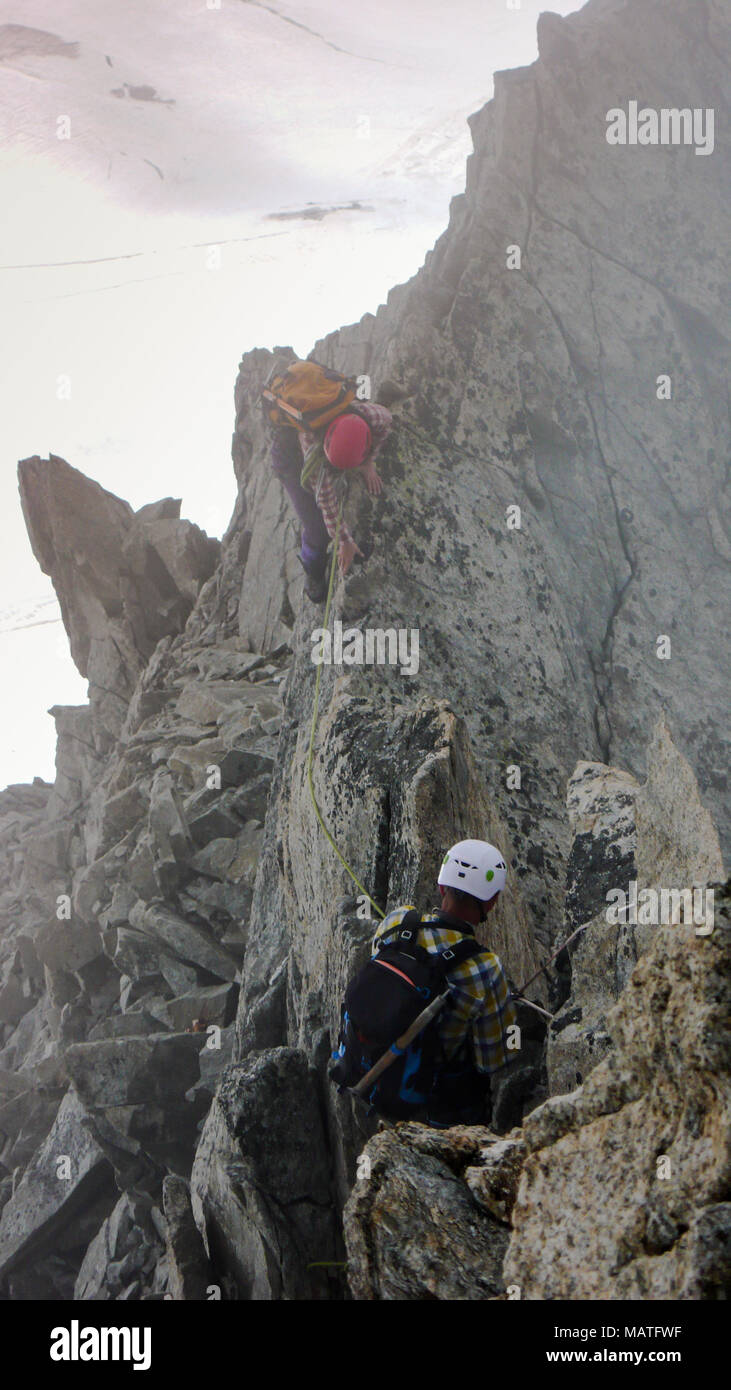 Guida di montagna e il client verso un alto vertice alpino su un nebbioso giorno Foto Stock