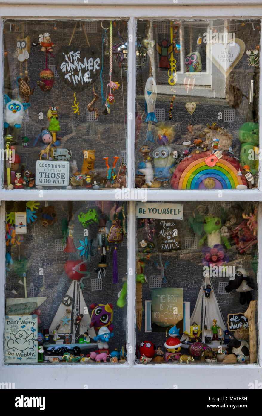 Un eclettico mix di giocattoli e di vari articoli interessanti nella finestra di un piccolo cottage costiere sul Cornish Coast. Il vecchio negozio di curiosità la finestra di visualizzazione Foto Stock