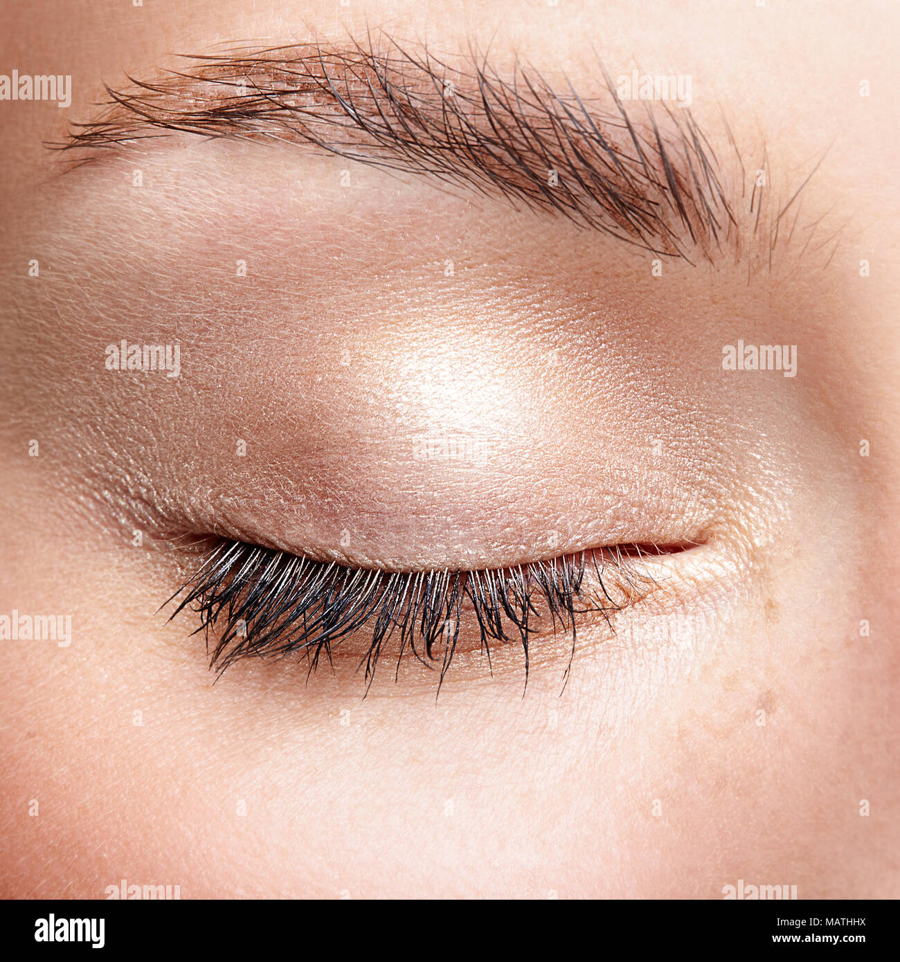 Macro Closeup colpo di umano chiuso occhio femmina. Donna con la naturale bellezza viso trucco. Ragazza con una pelle perfetta e lentiggini. Foto Stock