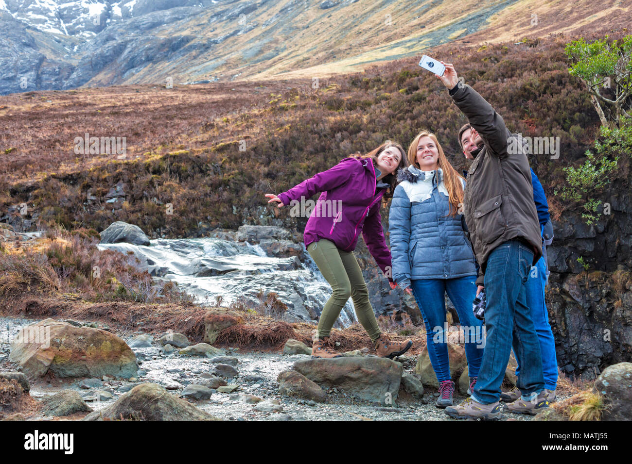 I turisti prendendo un selfie al Black Cuillin e fiabesco Piscine, fiume fragile, Isola di Skye in Scozia, nel Regno Unito nel mese di marzo Foto Stock