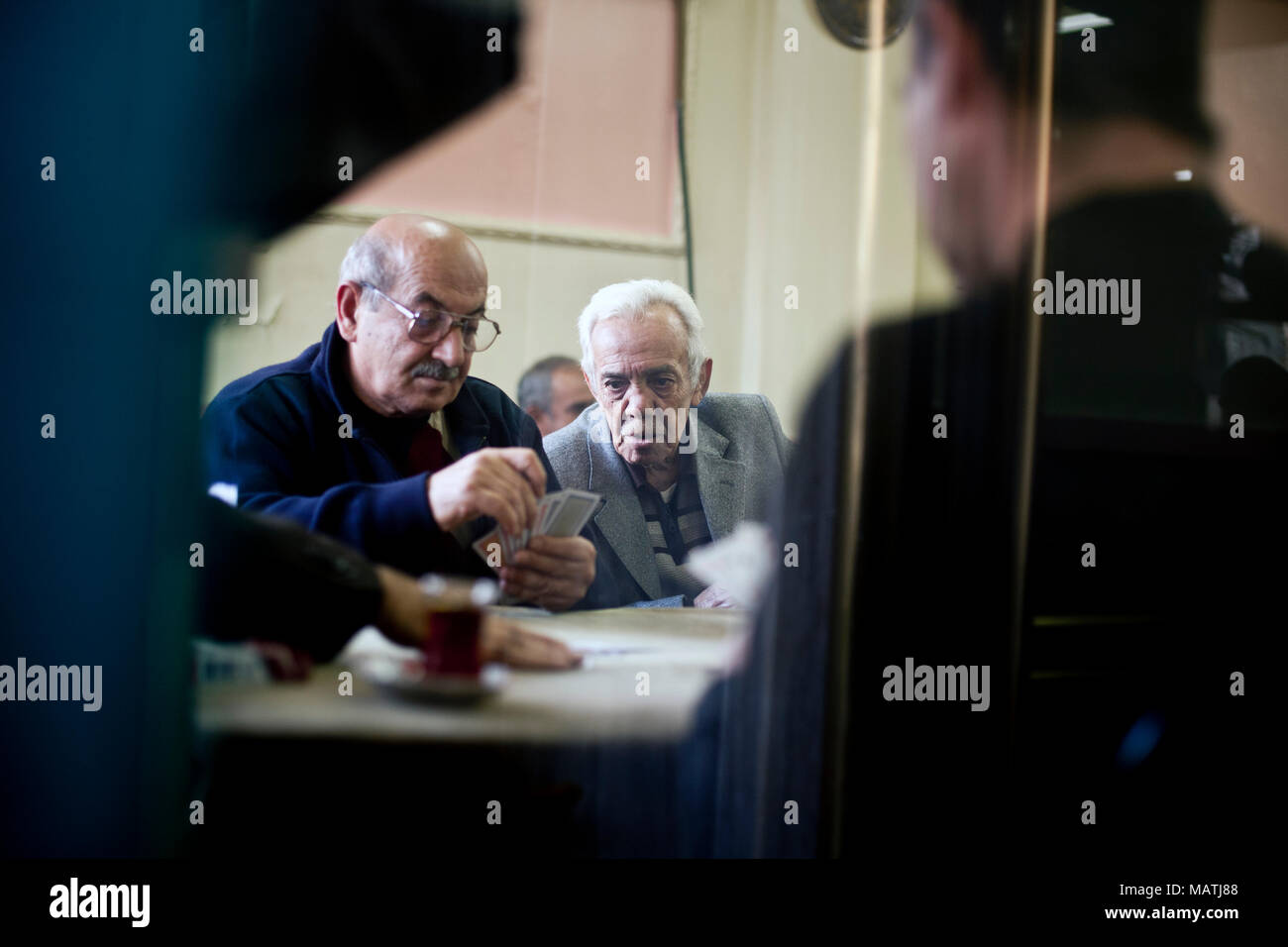 ISTANBUL, Turchia - 7 Novembre 2009: l'uomo guarda oltre la spalla di un altro giocando a carte all'interno di un cafe nel quartiere Fatih di Istanbul. Foto Stock