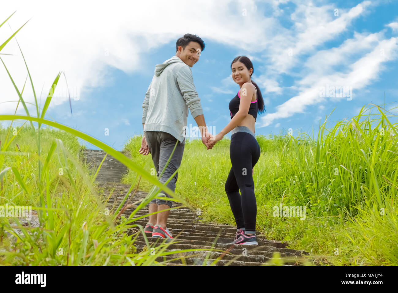 Coppia giovane jogging upstair in foresta, tenendo le mani insieme Foto Stock