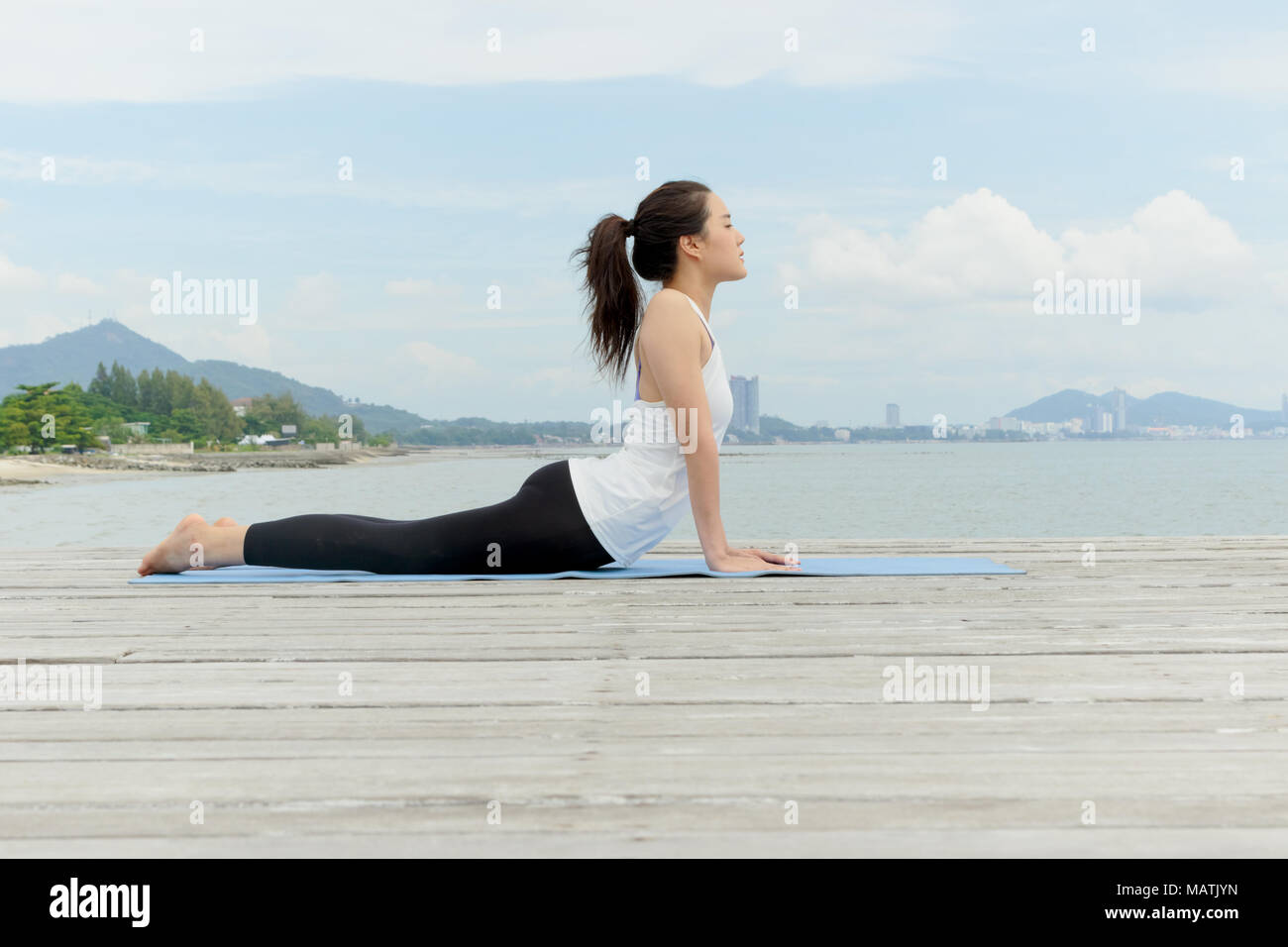 Giovane donna asiatica a praticare yoga al mare Foto Stock