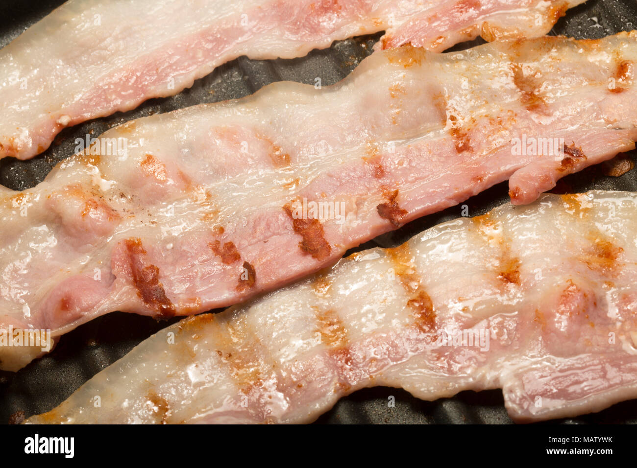 Striata, unsmoked pancetta UE da un supermercato fritti su un George Foreman riducendo il grasso Grill utilizzando il grasso naturale della pancetta. Regno Unito Foto Stock