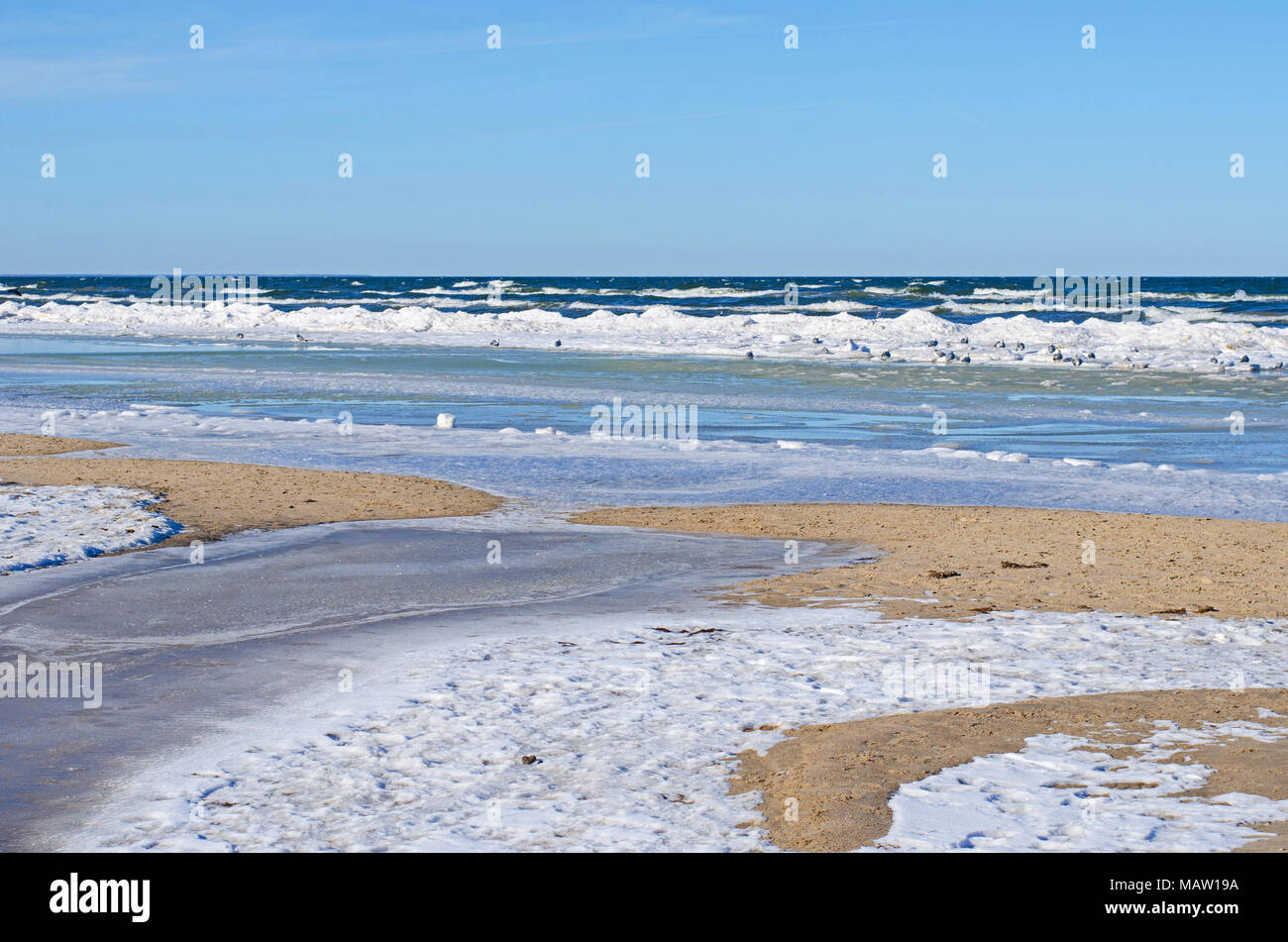 Molte sfumature di colori, forme e strutture di neve, ghiaccio e acqua alla riva sabbiosa del Mar Baltico in inverno Foto Stock
