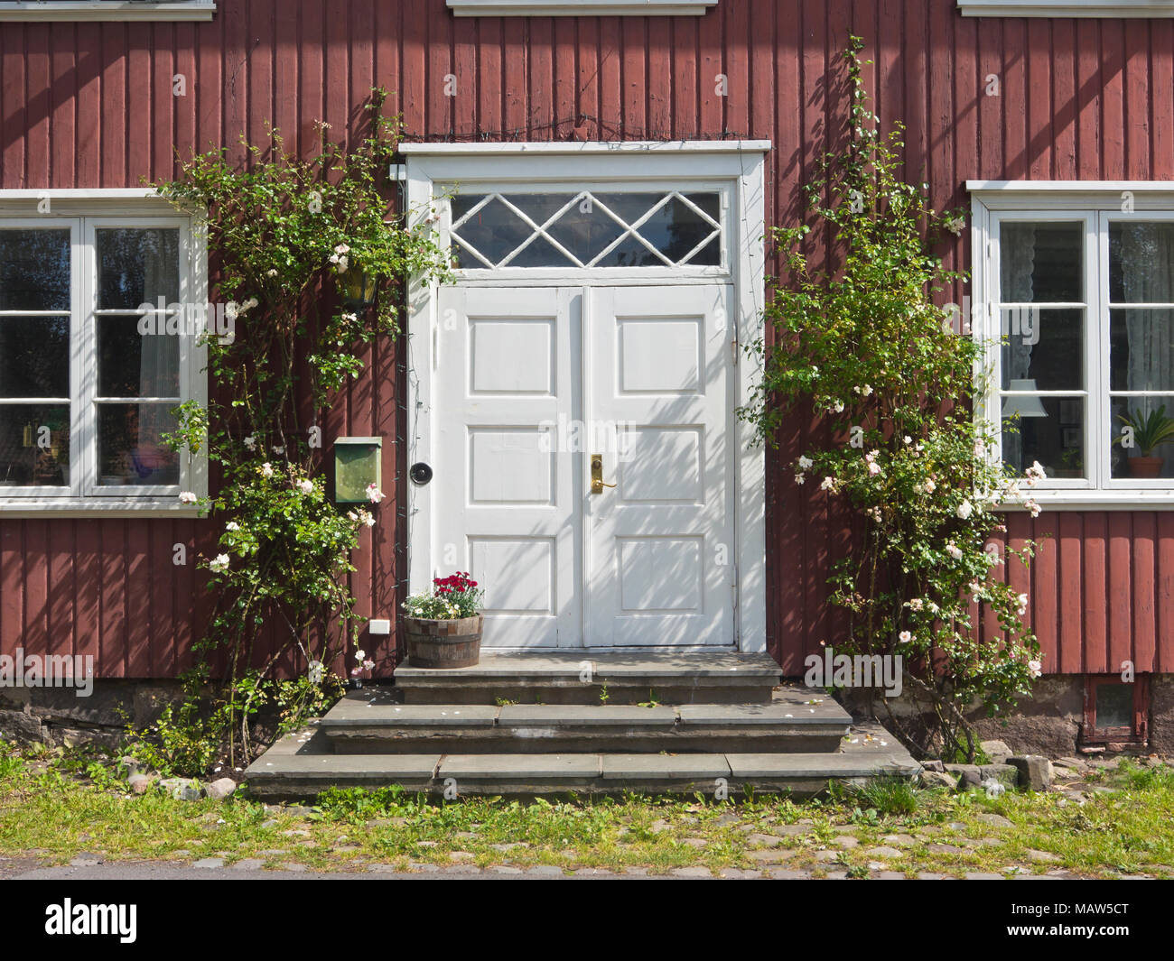 Sommer idilliaca immagine da Horten Norvegia, rosso vecchia casa in legno con porta bianca e rose rampicanti framing l'ingresso Foto Stock