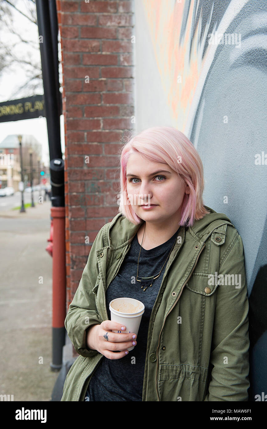 Una giovane donna con capelli rosa, tenendo una tazza di caffè a Portland, Oregon. Foto Stock
