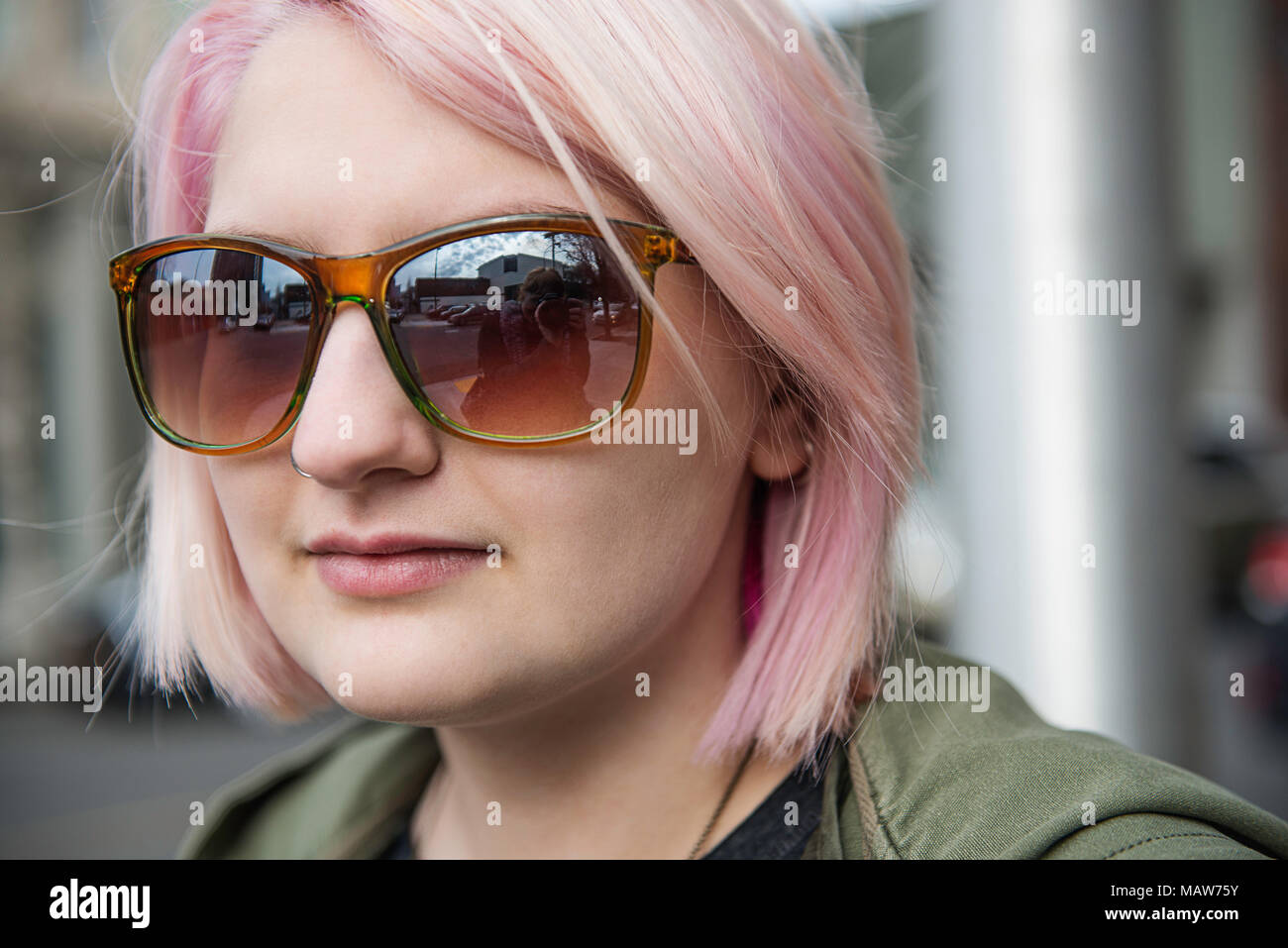 Una giovane donna con capelli rosa e un anello di naso. Foto Stock