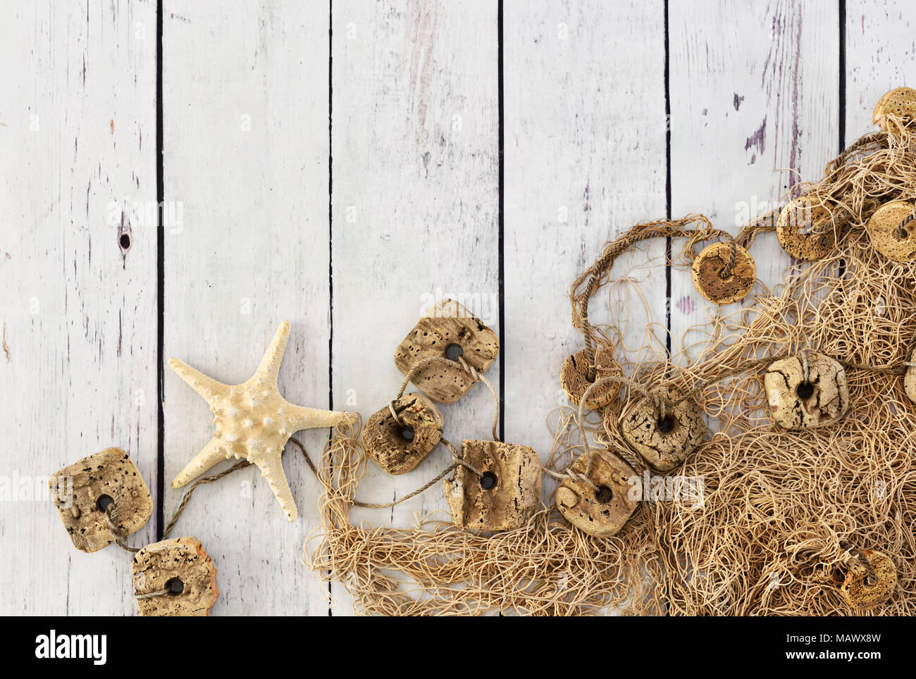 Rete da pesca o fisher net e tavole di bianco. Sfondo marittimo con stella di mare e lo sfondo di legno con copia spazio. Foto Stock