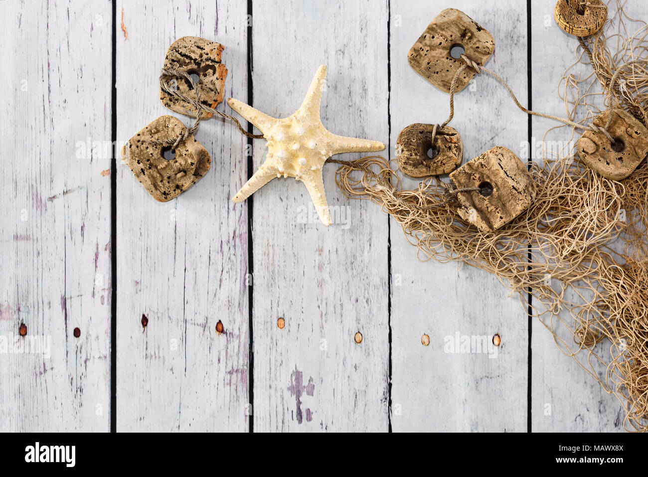 Rete da pesca o fisher net e tavole di bianco. Sfondo marittimo con stella di mare e lo sfondo di legno con copia spazio. Foto Stock