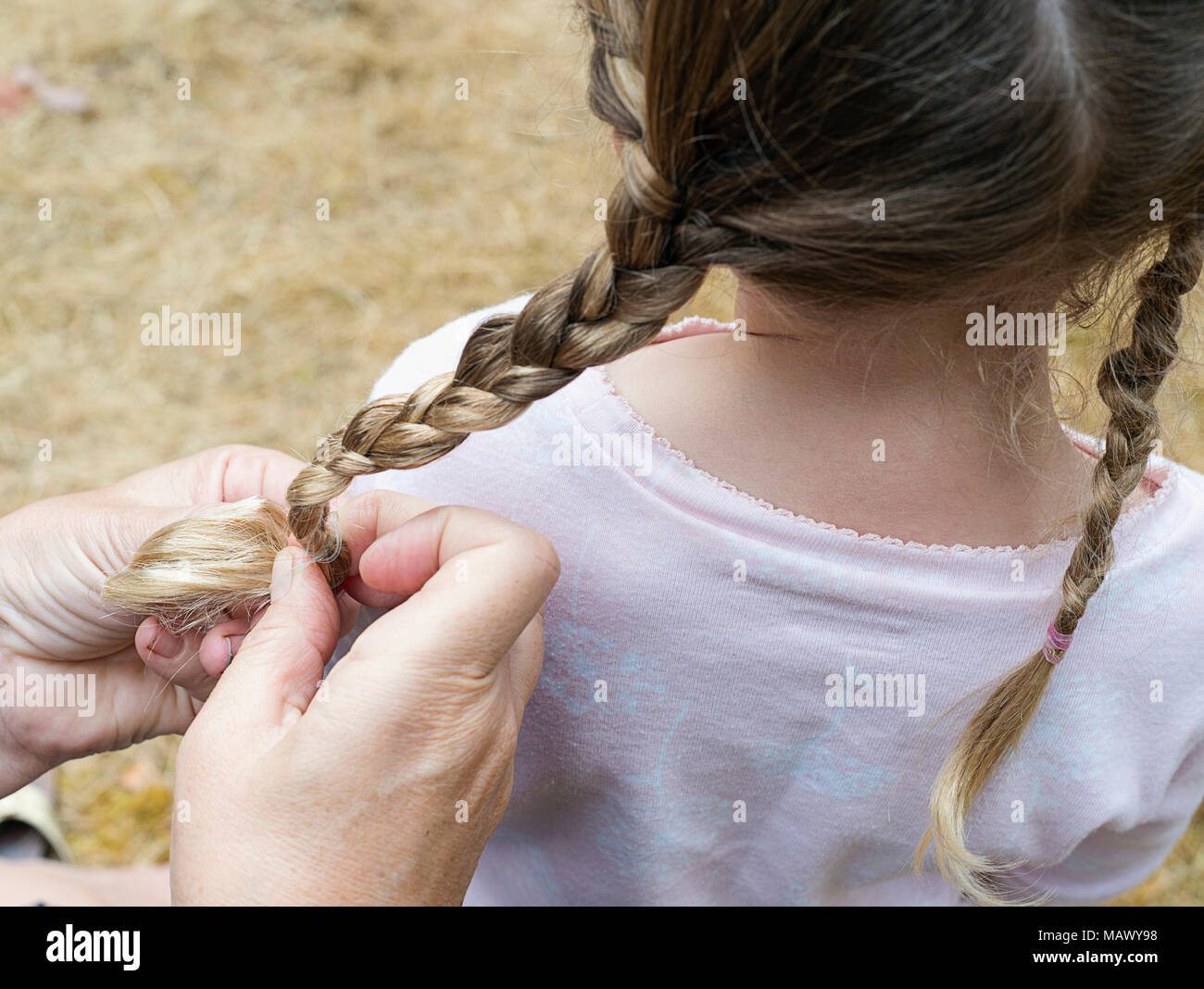 Una donna trecciatura in giovani ragazze capelli. Foto Stock