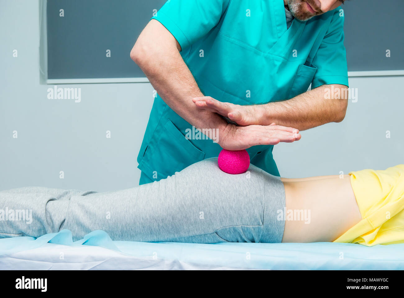 Donna alla ricezione di fisioterapia massaggio a sfera dal terapista. Un chiropratico tratta del paziente femore natica in ufficio medico. Neurologia, Osteopat Foto Stock