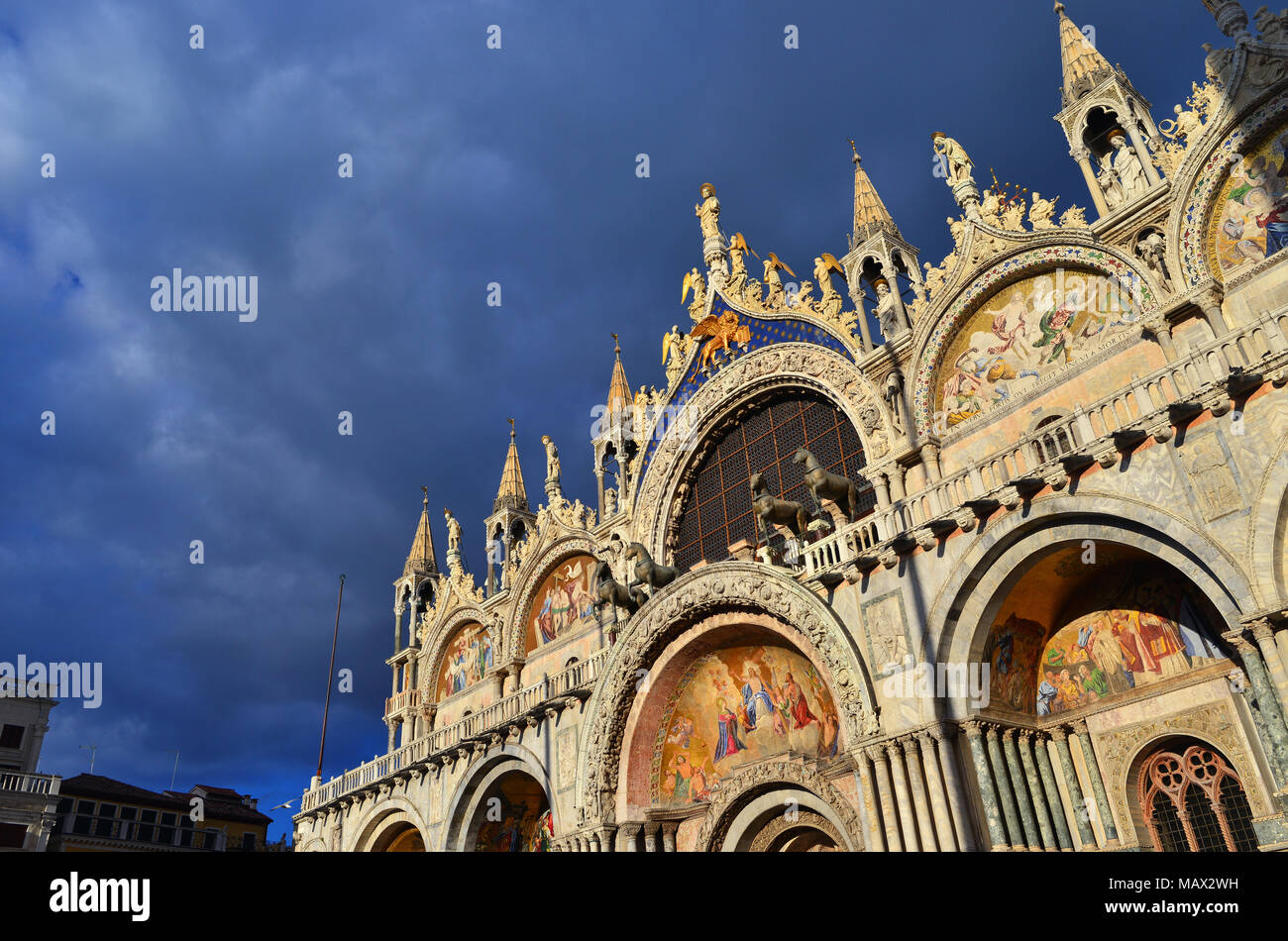 Bellissima gotica e bizantina la facciata della Basilica di San Marco a Venezia brilla al tramonto con il cielo nuvoloso Foto Stock