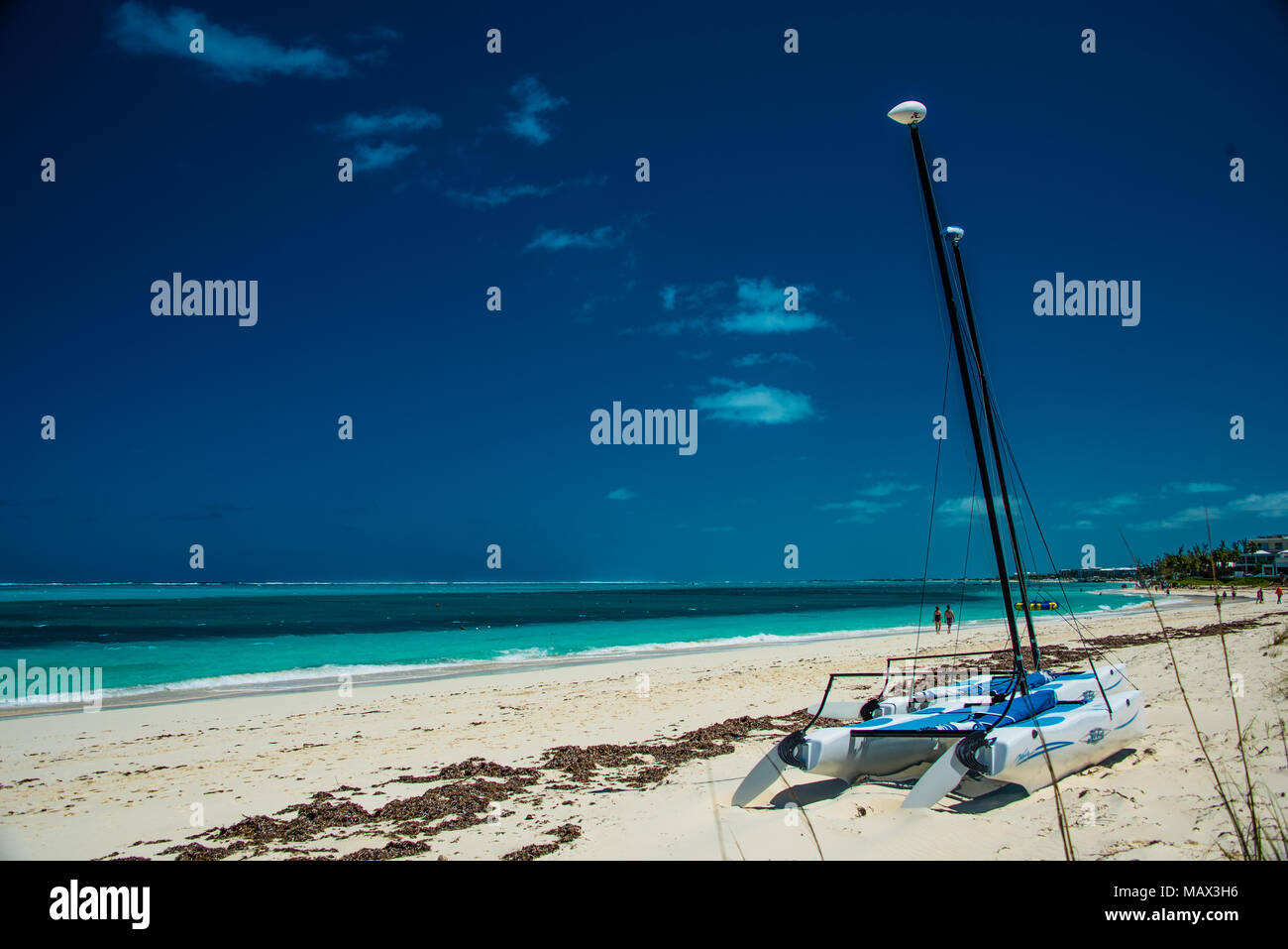 Idilliaco sabbiosa spiaggia tropicale nei Caraibi sulle Isole Turks e Caicos con un catamarano e barca a vela spiaggiata sulla sabbia dorata che si affaccia su un Foto Stock
