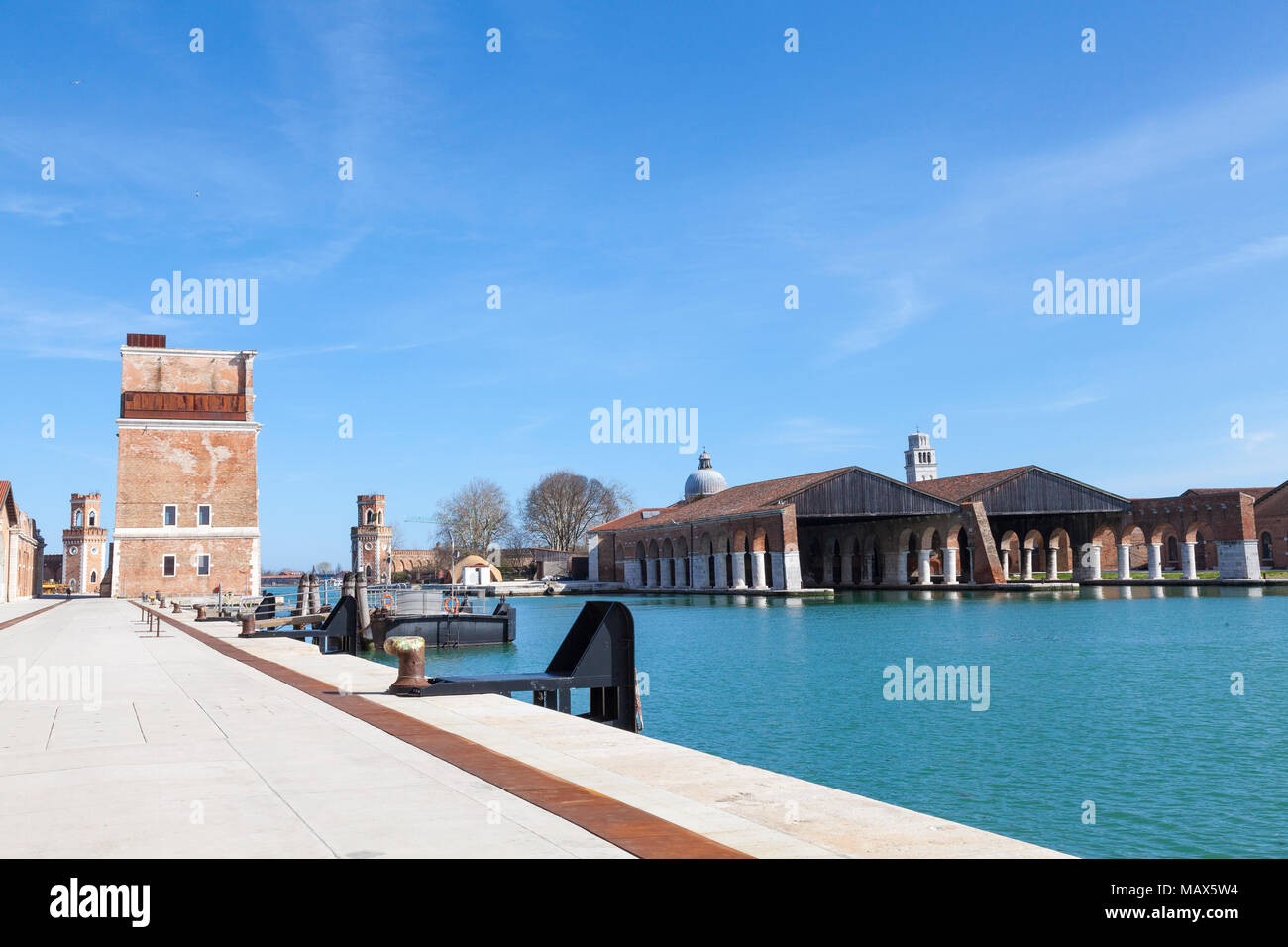 Vista attraverso la Darsena Nuovissima, Arsenale, Venezia, Veneto, Italia cercando lungo la banchina alla restaurata Porta Nova torre e due torri di controllo Foto Stock