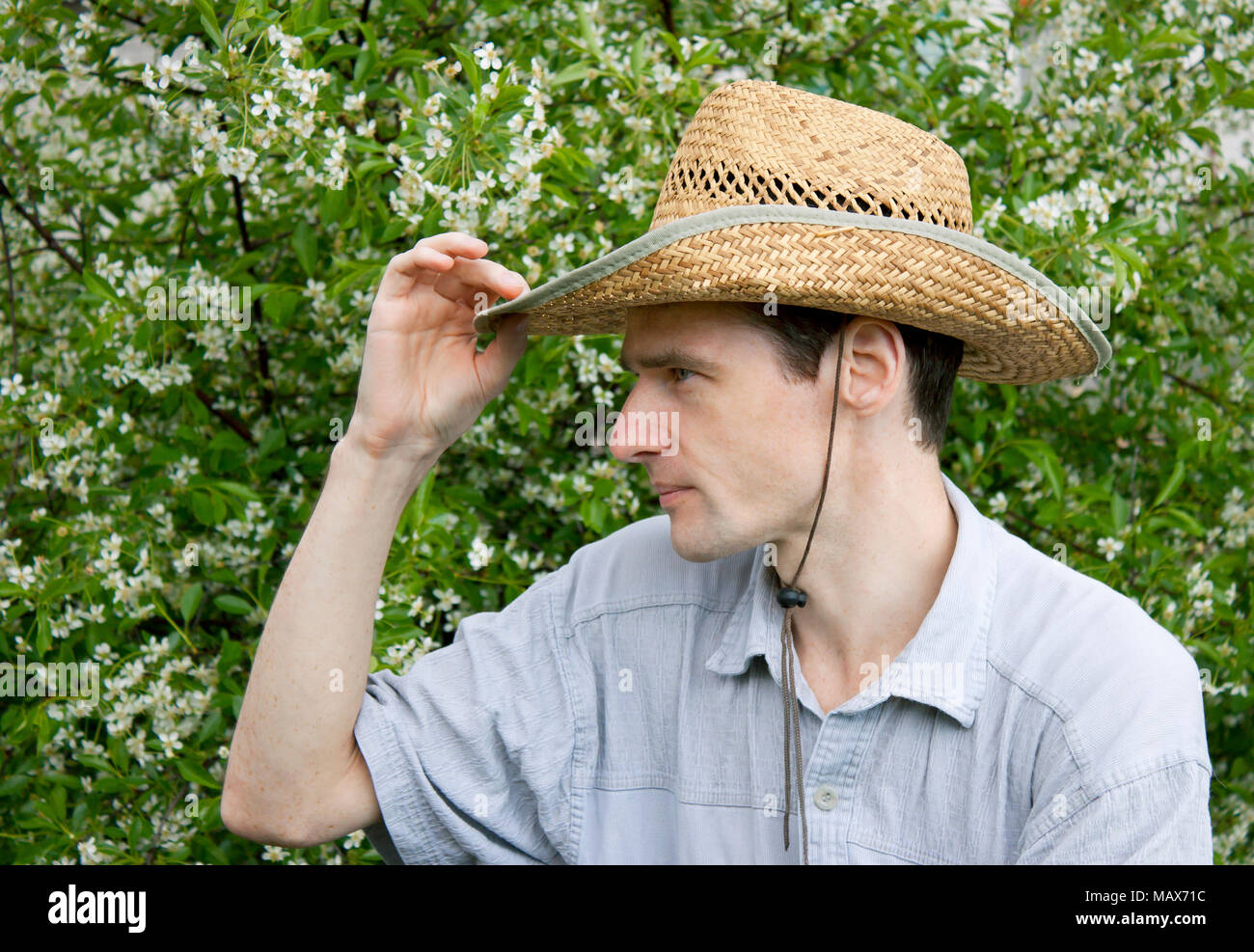 Un giovane uomo in un giardino di ciliegio in primavera Foto Stock