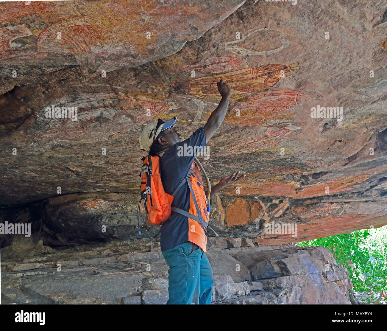 Guida aborigena sottolinea incredibile arte rock ai turisti su Anjalak Hill, vicino Gunbalanya di Arnhem Land, Territorio del Nord, l'Australia Foto Stock