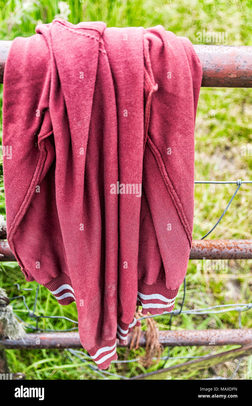 Un rosso lana cardigan appesa sopra una recinzione in acciaio Foto Stock