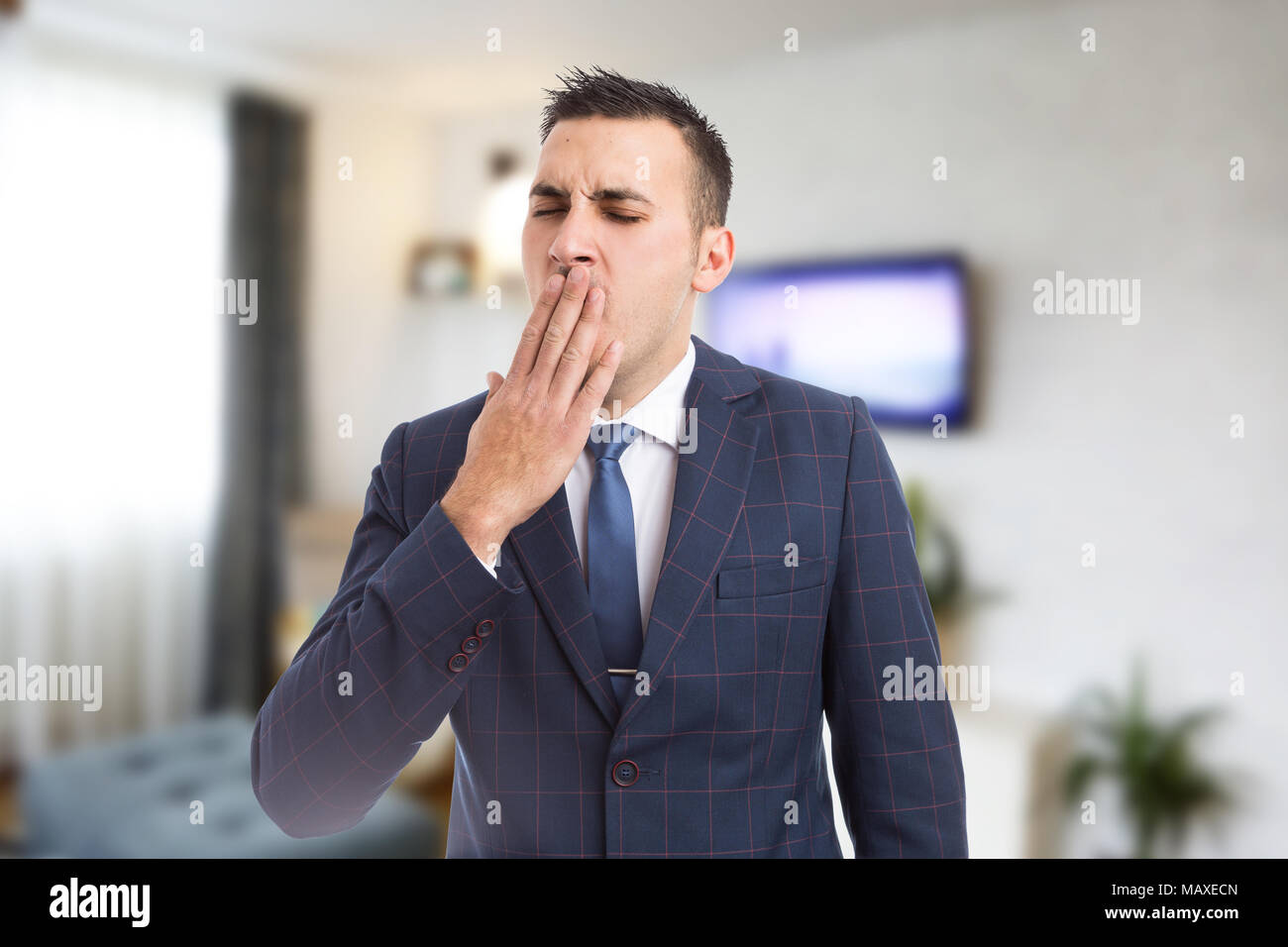 Giovane uomo d affari o agente immobiliare a sbadigliare come stanchezza concetto su appartamento sfondo in camera Foto Stock
