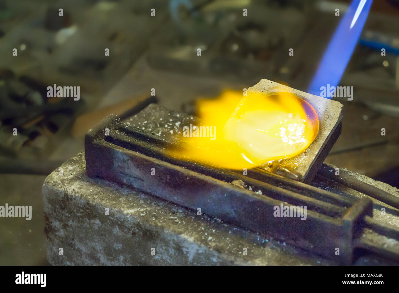 Gioielliere mettendo in argento di fusione sul filo lingottiera mediante un gas - ossigeno torcia. Foto Stock