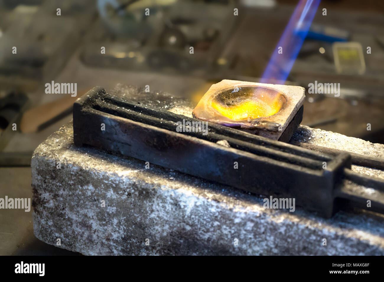 Gioielleria in argento di fusione su una ceramica melting pot con una torcia a gas e un filo lingottiera pronto per l'uso. Foto Stock