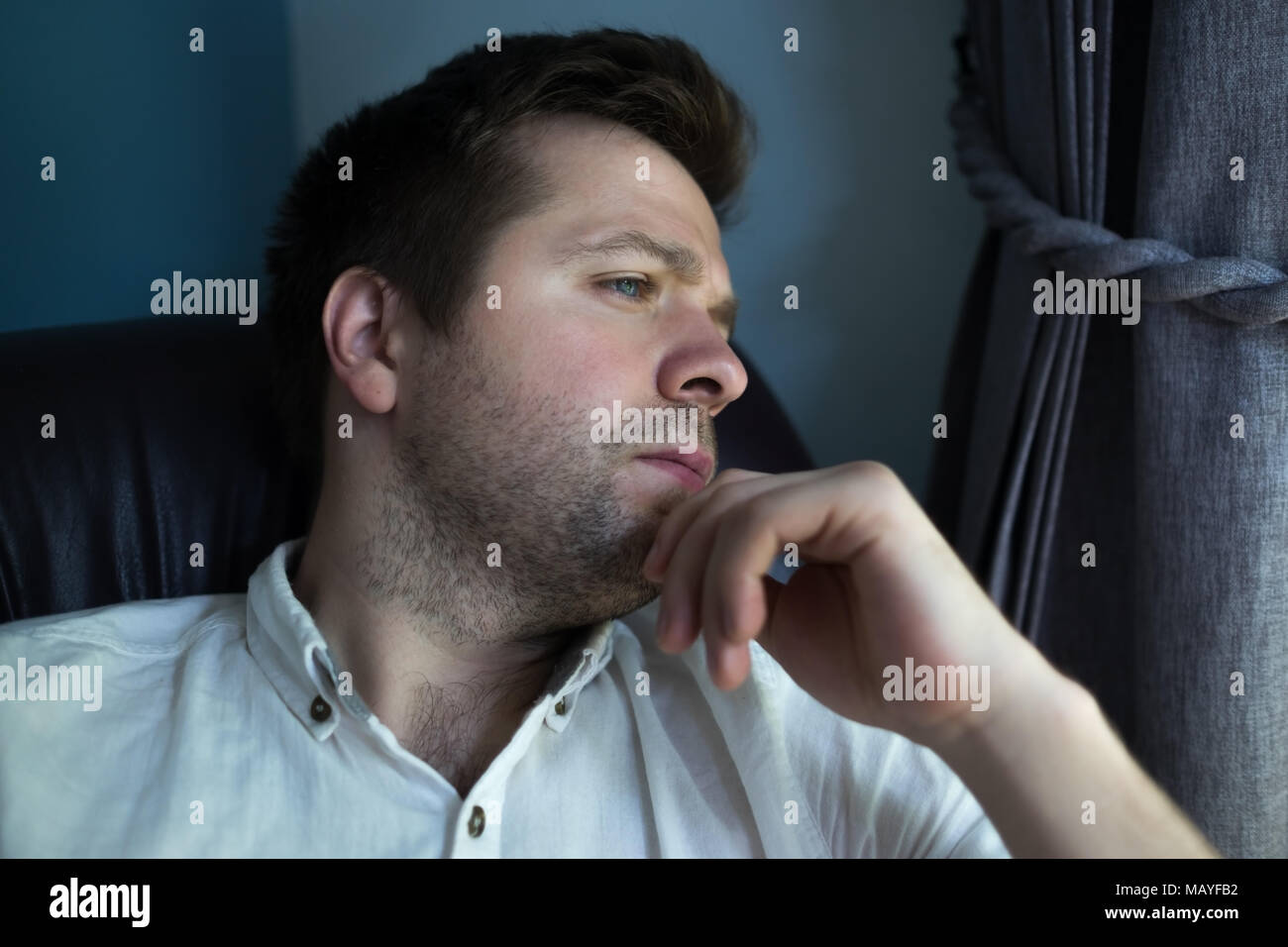 Uomo caucasico seduto in divano nero nella triste umore. Egli sta pensando di piani futuri o problemi Foto Stock