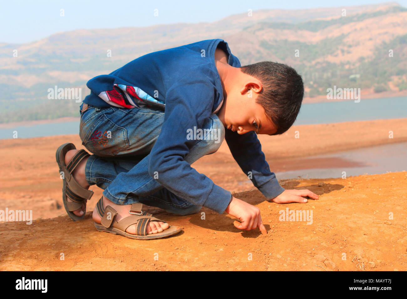 Little Boy iscritto sul terreno con il suo dito a Tamihini ghat a Pune Foto Stock