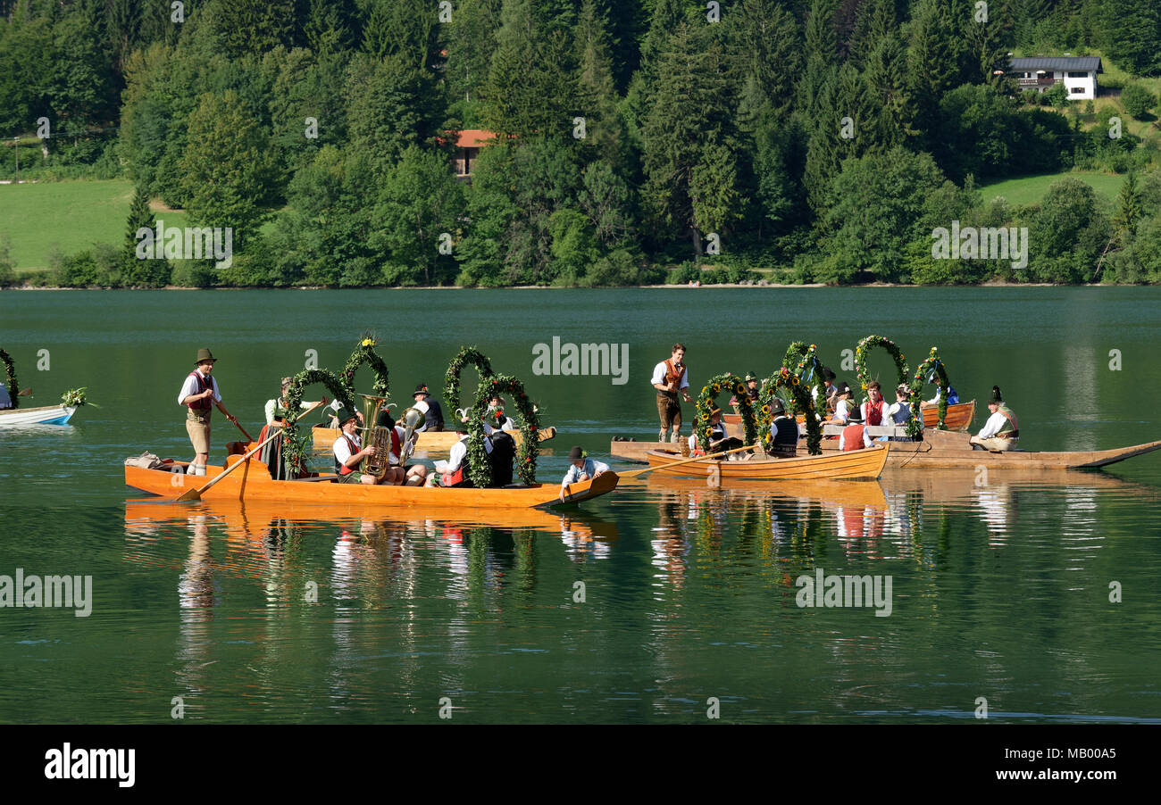 Uomini che indossano costumi tradizionali in addobbate a festa le piazze, barche in legno sul lago Schliersee, Alt-Schlierseer-Kirchtag Foto Stock