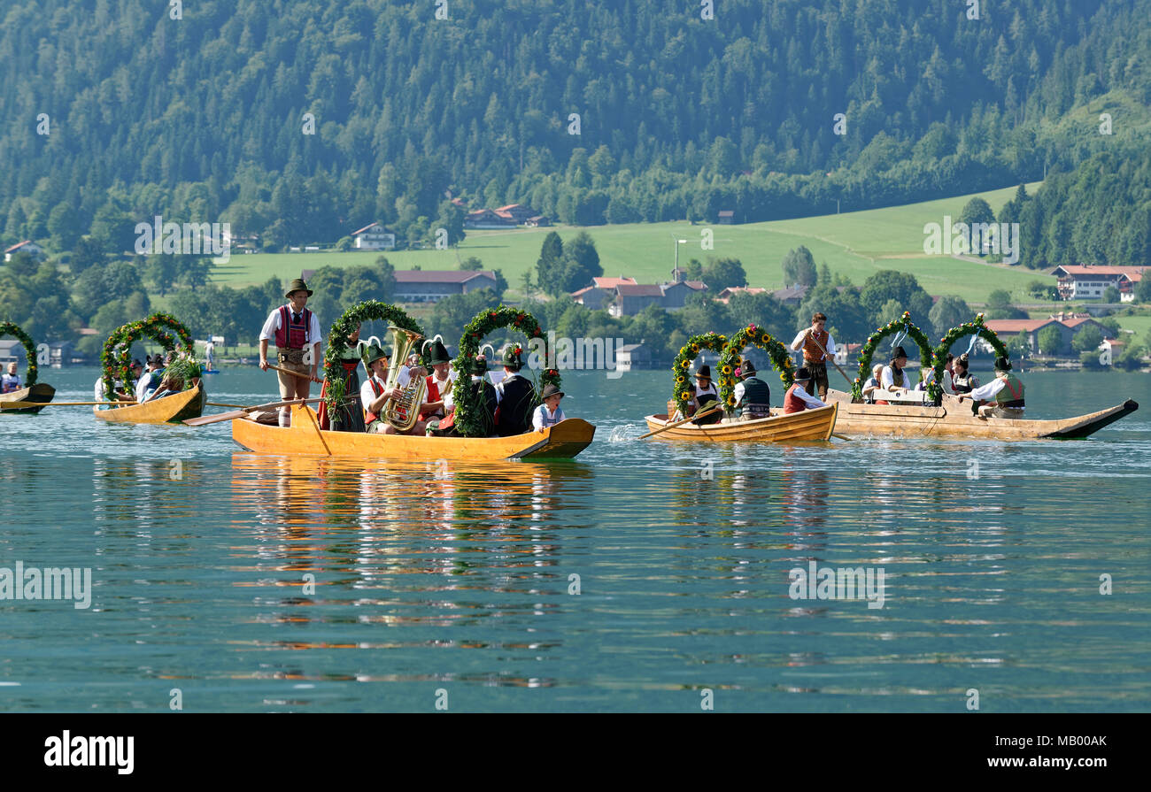 Uomini che indossano costumi tradizionali in addobbate a festa le piazze, barche in legno sul lago Schliersee, Alt-Schlierseer-Kirchtag Foto Stock