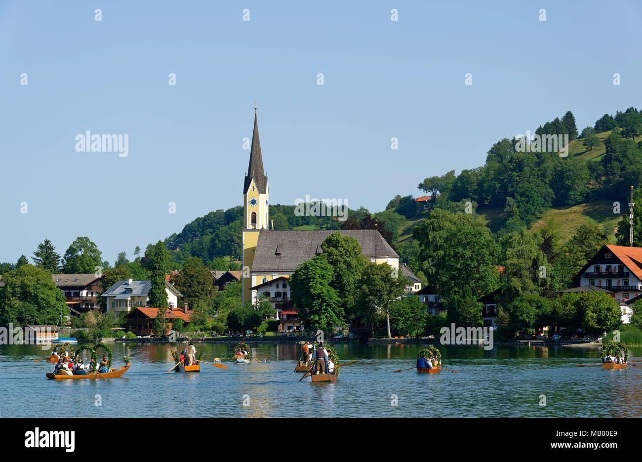 Uomini che indossano costumi tradizionali in addobbate a festa le piazze, barche in legno sul lago Schliersee, vista di Schliersee con Foto Stock