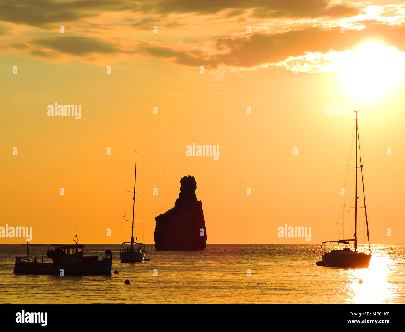 Tramonto di scena a Spiaggia Benirras, Isola di Ibiza. Formazione di roccia e sunbeam, vacanze estate scena. Foto Stock