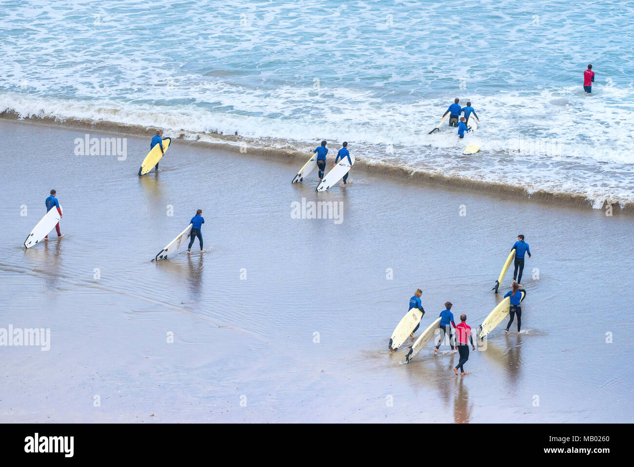 I giovani che trasportano le loro tavole da surf all inizio della loro lezione di surf. Foto Stock