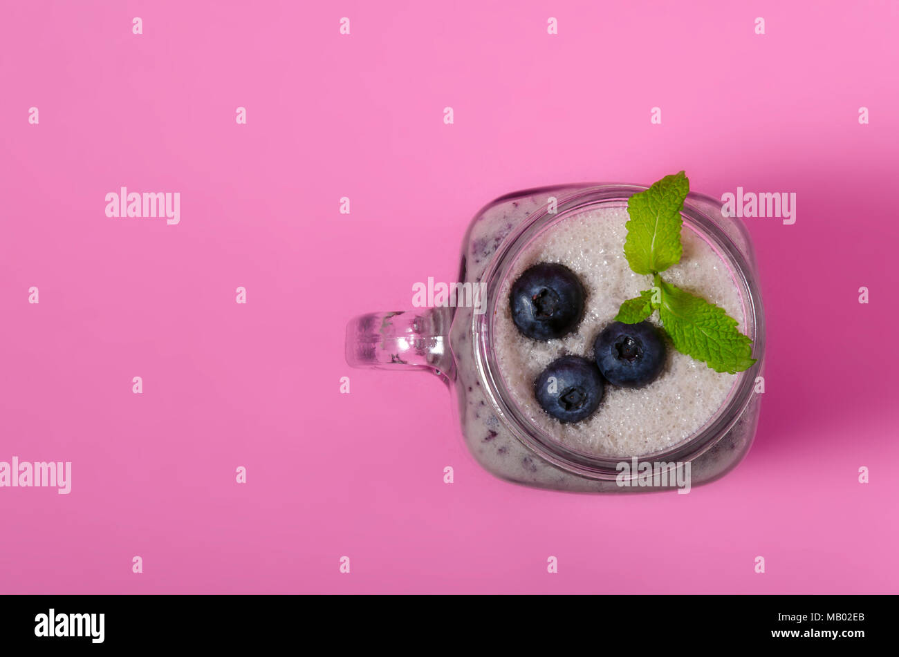 Frullato di mirtilli con menta in mason vasetto di vetro con bacche e foglie di menta. Al di sopra di vista sulla tabella di rosa. Cibo sano. Foto Stock
