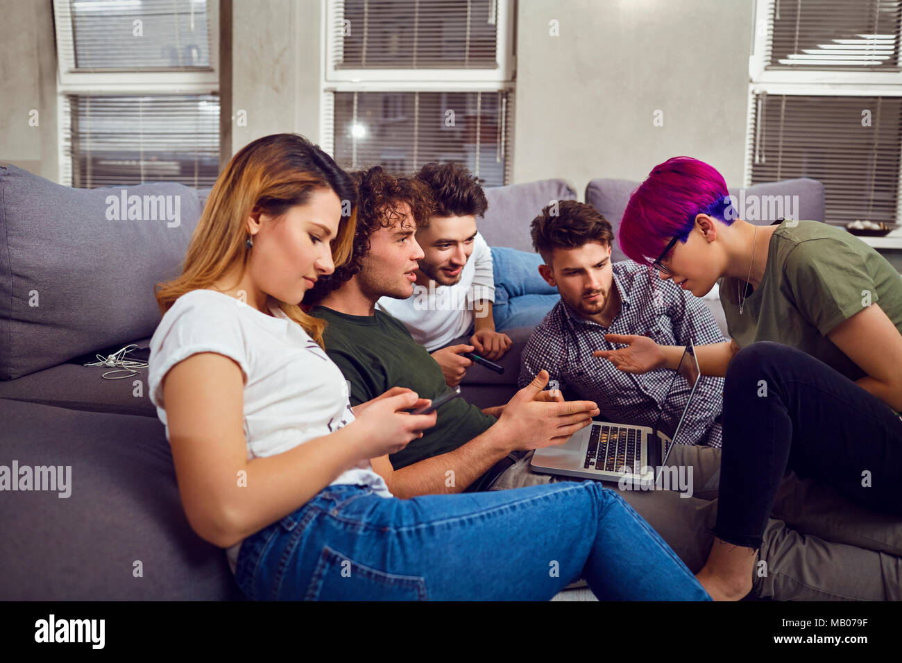 Un gruppo di amici degli studenti nel tempo libero con un computer portatile in un roo Foto Stock