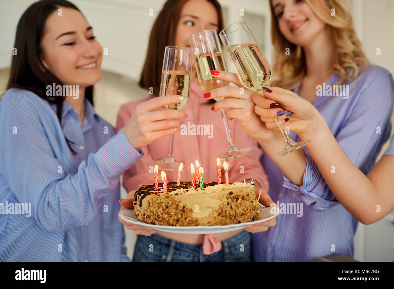 Una torta con candeline per il compleanno nelle mani delle ragazze c Foto Stock