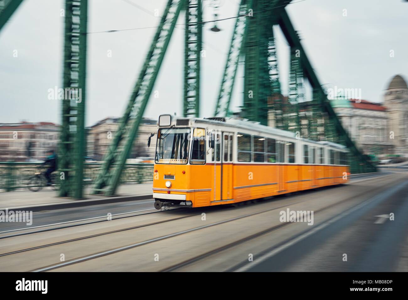 Il vecchio tram giallo in moto sul ponte in ferro. La vita della città di Budapest, Ungheria. Foto Stock