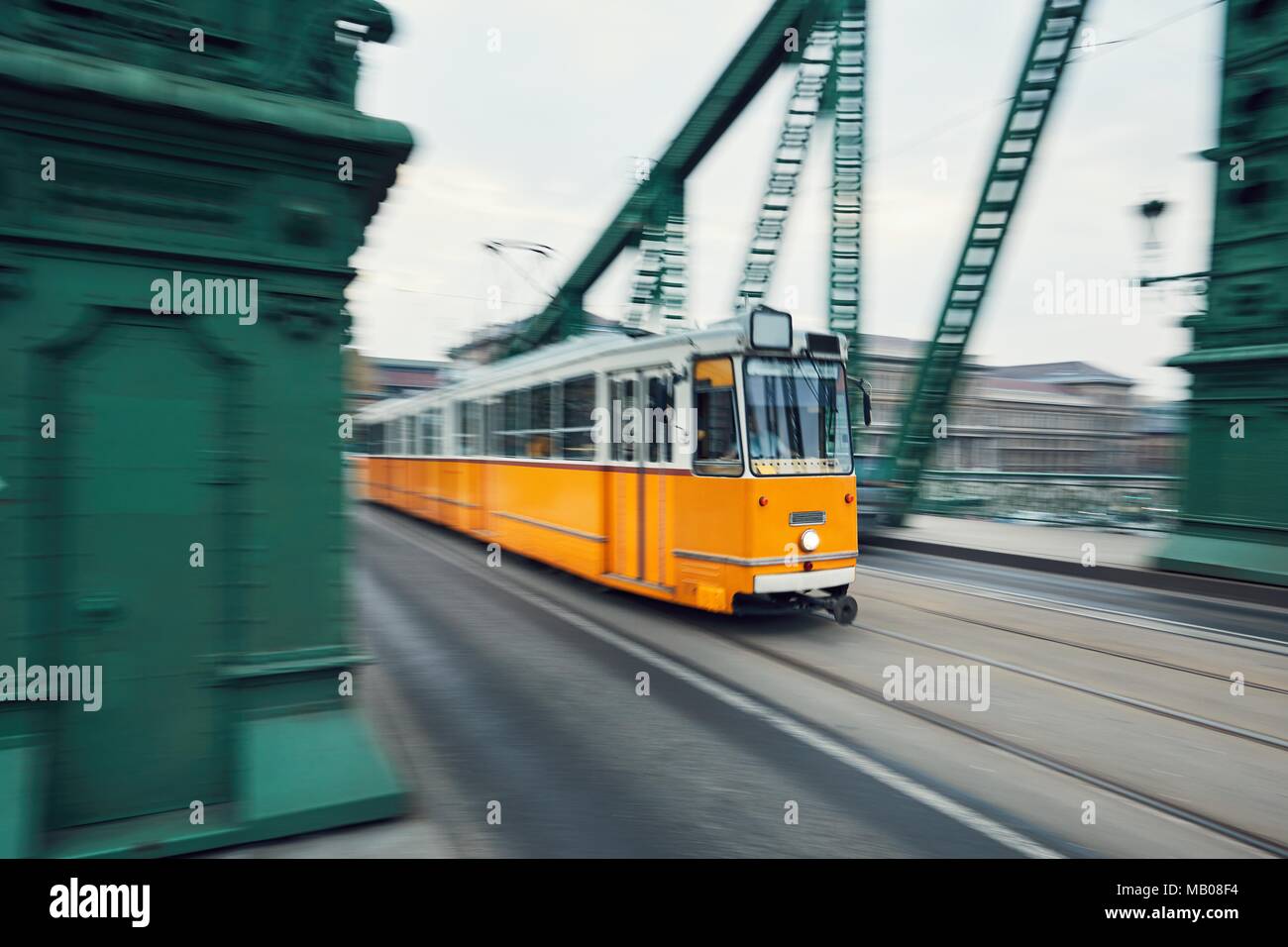 Il vecchio tram giallo in moto sul ponte in ferro. La vita della città di Budapest, Ungheria. Foto Stock