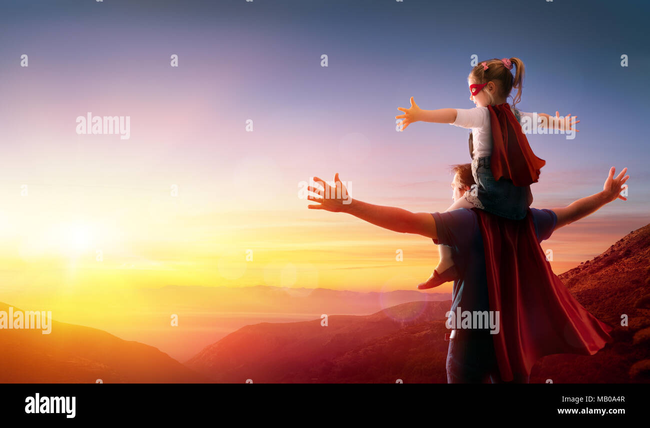 Mia figlia e suo padre vestito come eroi di guardare il tramonto Foto Stock