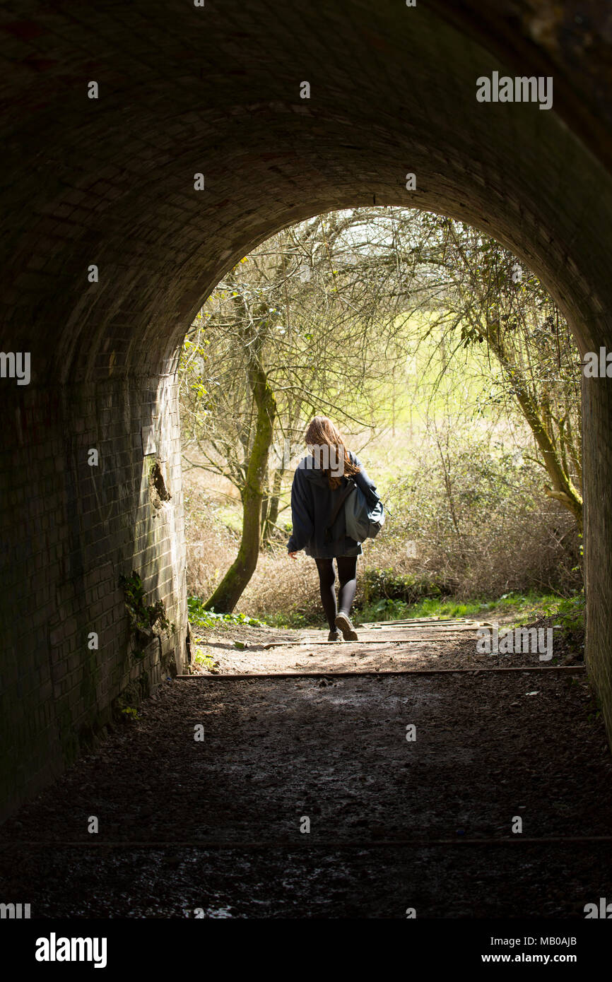 Una giovane ragazza camminare attraverso un tunnel sotto un ponte ferroviario. Regno Unito Foto Stock