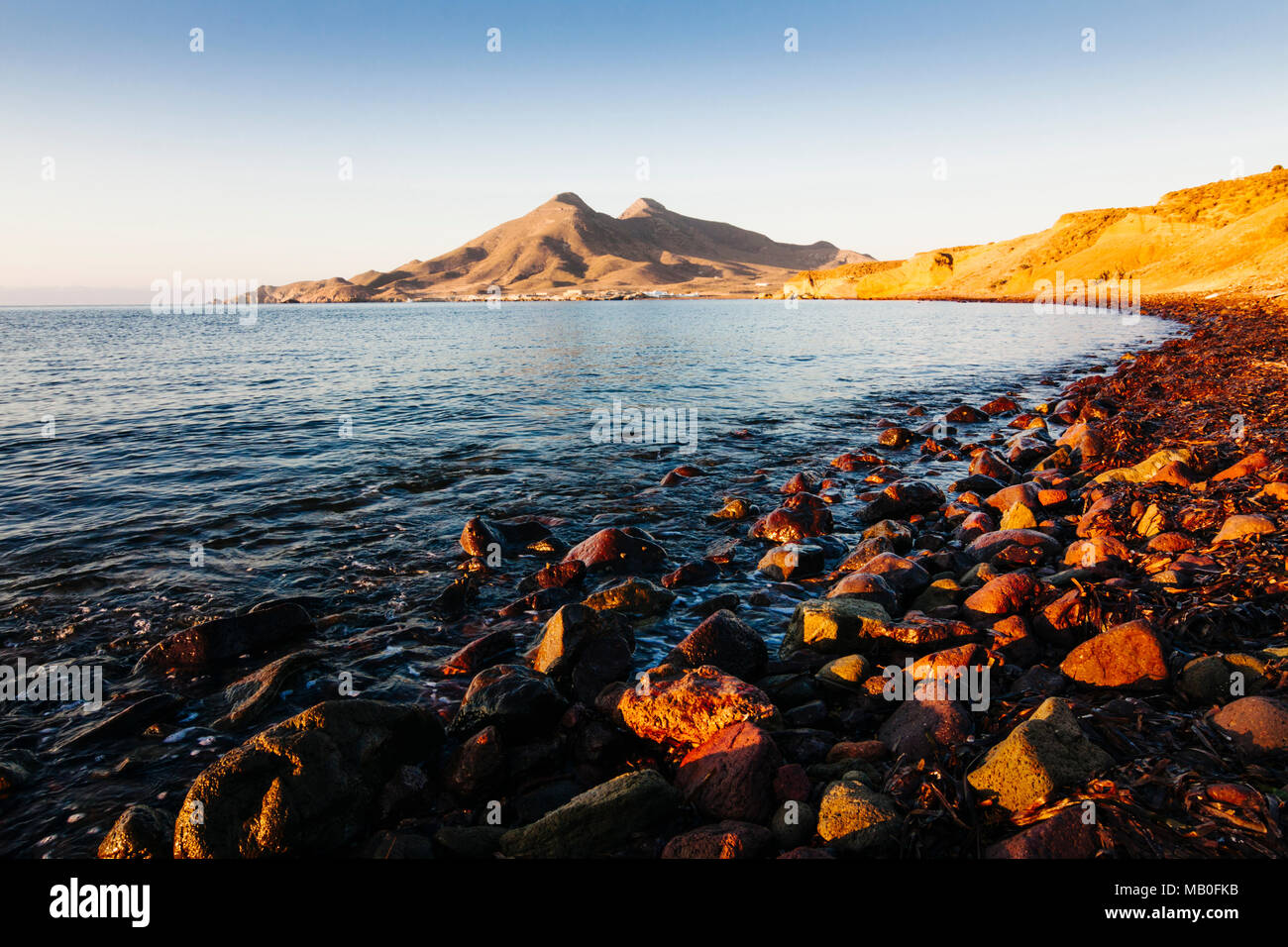 Isleta del Moro, Cabo de Gata-Nijar parco naturale, provincia di Almeria, Andalusia, Spagna : Alba a deserta spiaggia rocciosa con Los Frailes stinct volcan Foto Stock