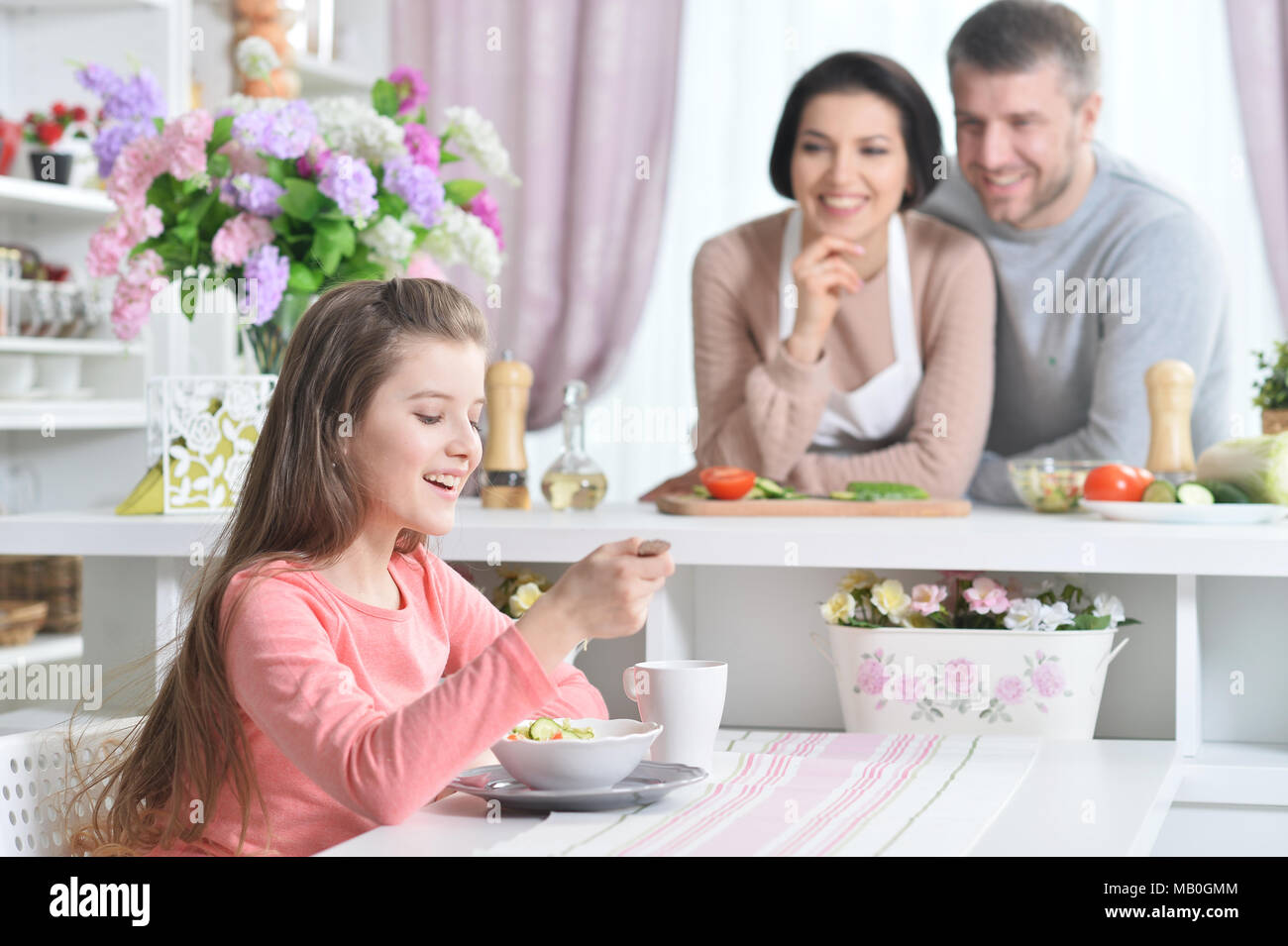 Ragazza sorridente mangiando in cucina Foto Stock