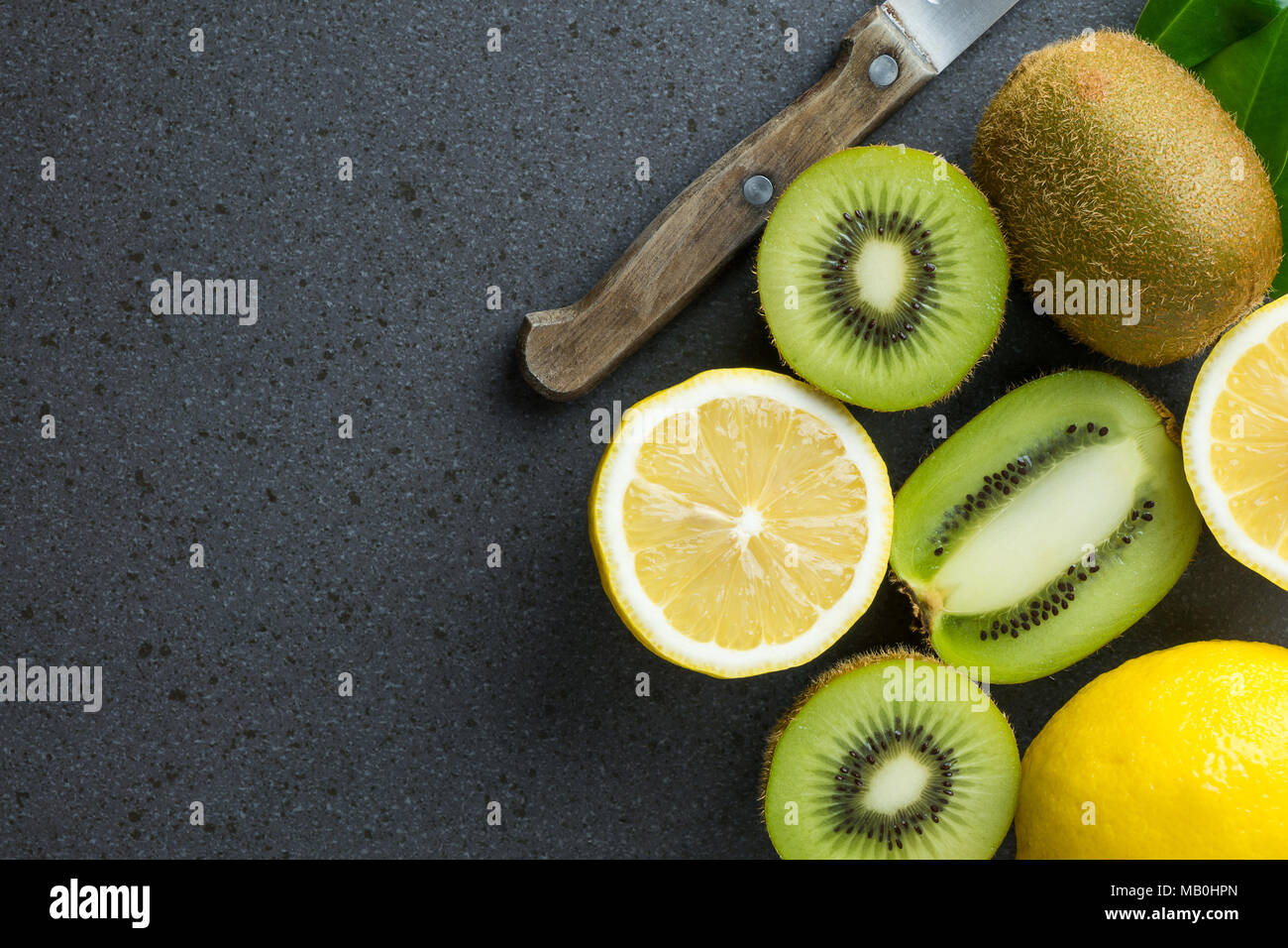 I limoni e kiwi frutti sono sulla parte superiore di nero tavolo da cucina. Vista da sopra con copia spazio, laici piana. Foto Stock