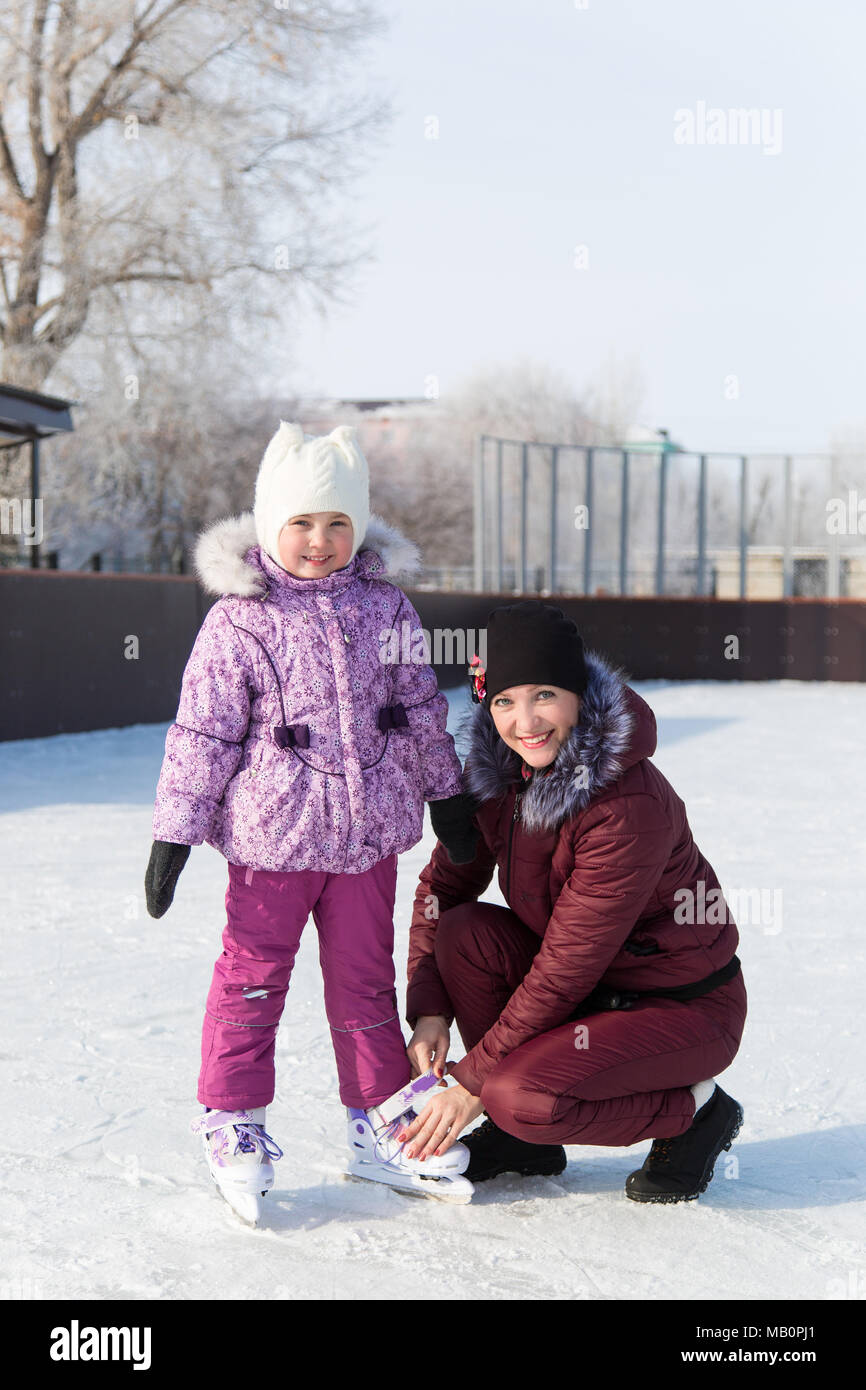 Una donna con una bambina su ghiaccio impara a pattinare d'inverno. Foto Stock
