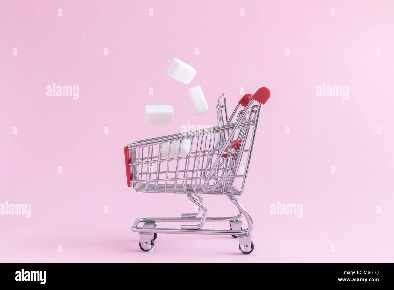 Zollette di zucchero che rientrano nel piccolo carrello Modello giocattolo sul rosa pastello minima di sfondo concetto creativo. Foto Stock