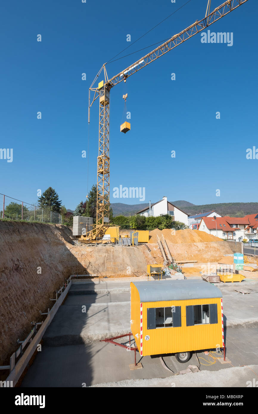 Sito in costruzione con giallo rimorchio del sito e la gru Foto Stock