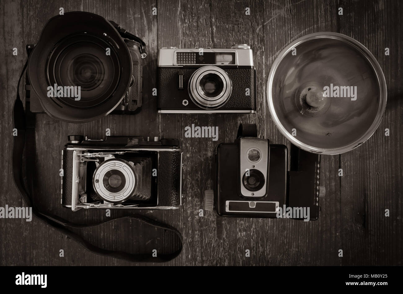 Close up foto in bianco e nero di una selezione di film vintage telecamere con una DSLR Moderna su uno sfondo di legno stagionato. Foto Stock
